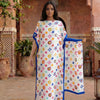 A woman models a floral print satin maxi shawl in white and blue on an outdoor patio.