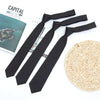 A set of classic solid black neckties for men and women laid out next to a ball of natural woven twine.