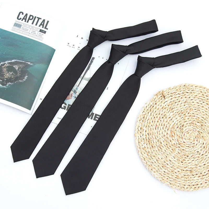 A set of classic solid black neckties for men and women laid out next to a ball of natural woven twine.
