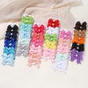 A collection of colorful handmade ribbon bow hair clips in various shades and patterns arranged on a white background.