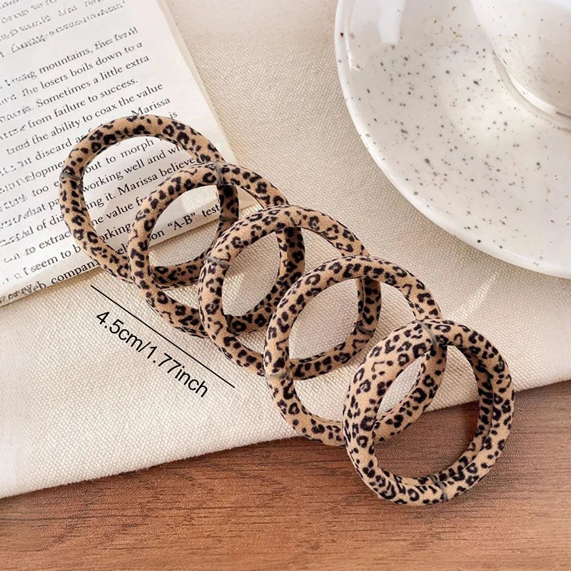 A stack of leopard print elastic hair ties is displayed on a piece of paper.