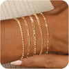 A stack of dainty gold plated bracelets worn on a wrist.
