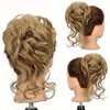 A woman's head showing a curly blonde hair bun hairstyle with loose curls.