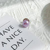 A pink pearl button set resting on a white card against a textured white background.
