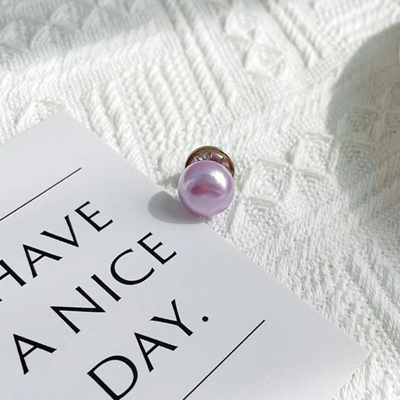 A pink pearl button set resting on a white card against a textured white background.