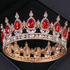 Couronne ton oro avec des gemmes rouges et des cristaux clairs, ressemblant à une tiara de strass baroque.