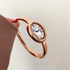 A close-up shot of a rose gold vintage quartz analog watch with an oval face being held by a hand.