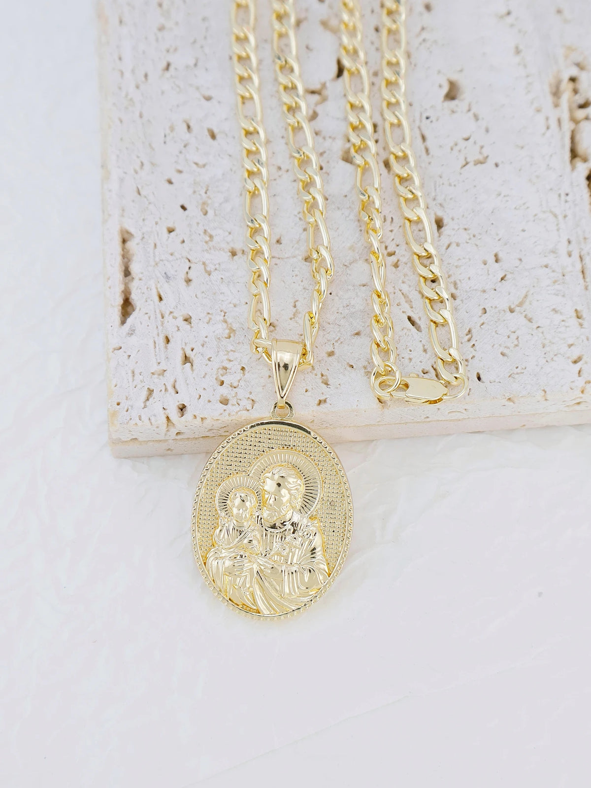 A gold-plated pendant necklace featuring a depiction of the Virgin Mary and Christ on a circular disc.