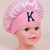 Pink satin sleep cap for kids with a black letter K design