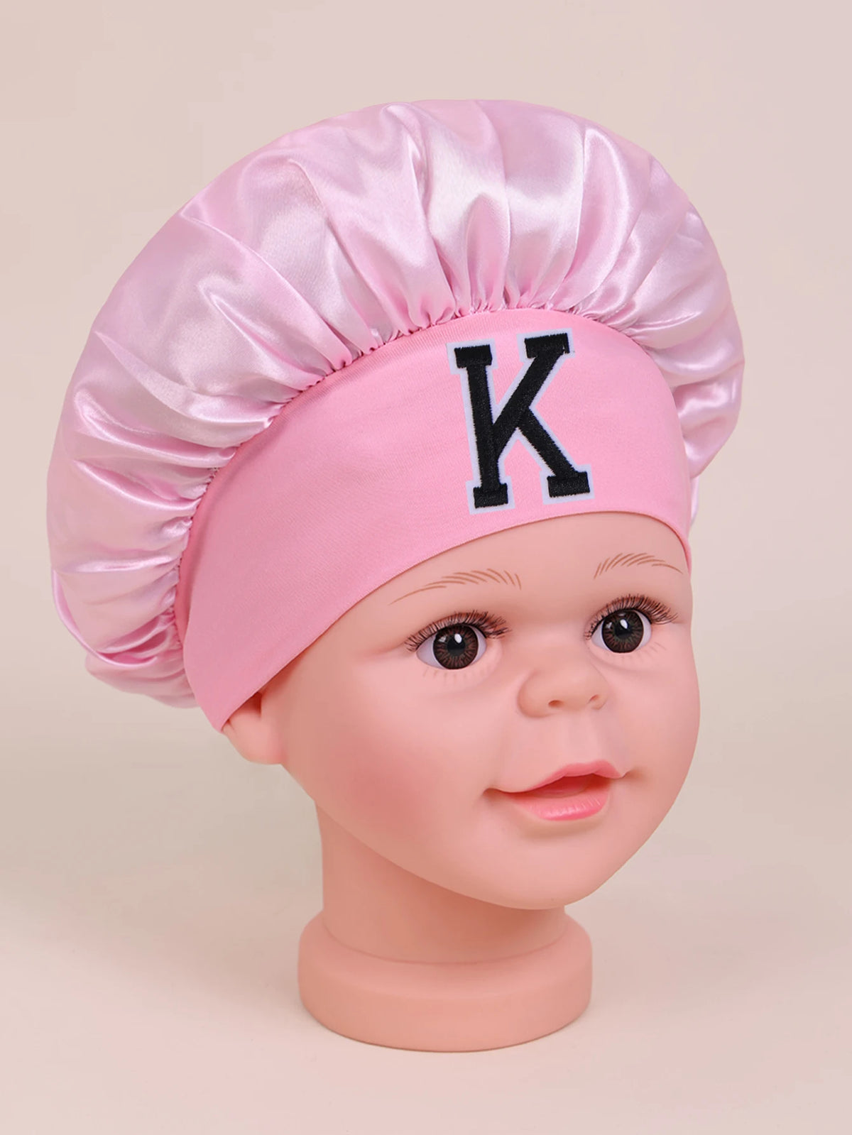 Pink satin sleep cap for kids with a black letter K design