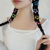 Primer plano del cuello y pecho de una mujer con cabello negro trenzado adornado con clips con forma de estrella coloridos.