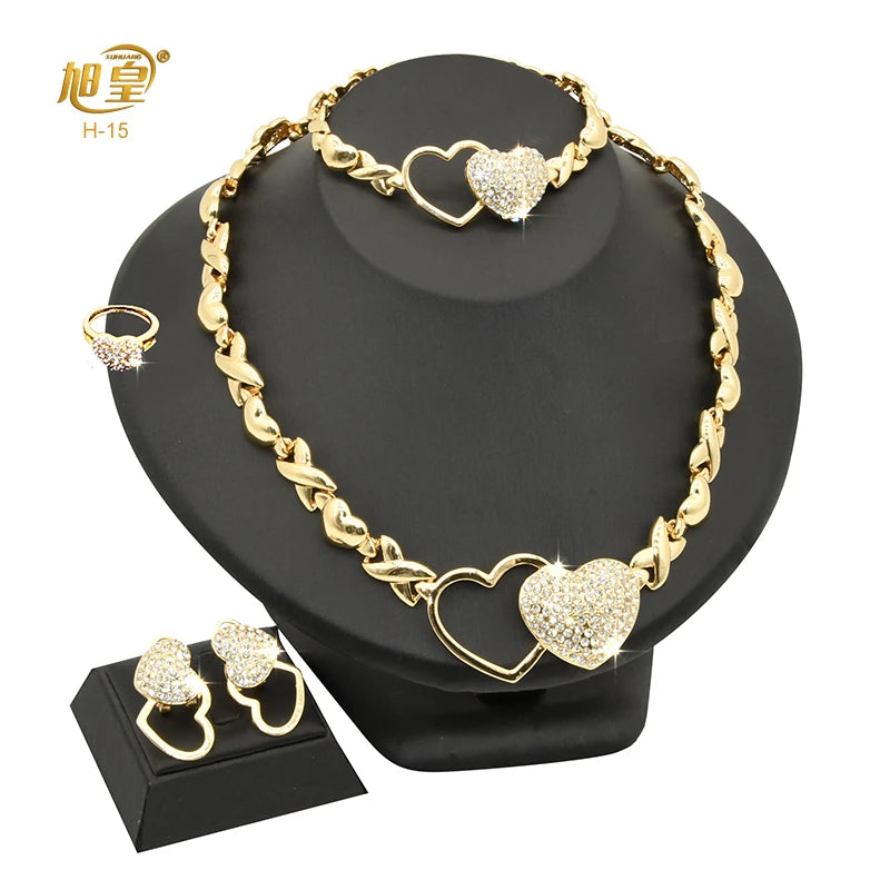 A gold heart crystal jewelry set featuring a necklace and pair of earrings displayed on a black stand.