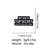 Pin de esmalte negro con el texto 'MY JOB IS TOP SECRET' grabado.