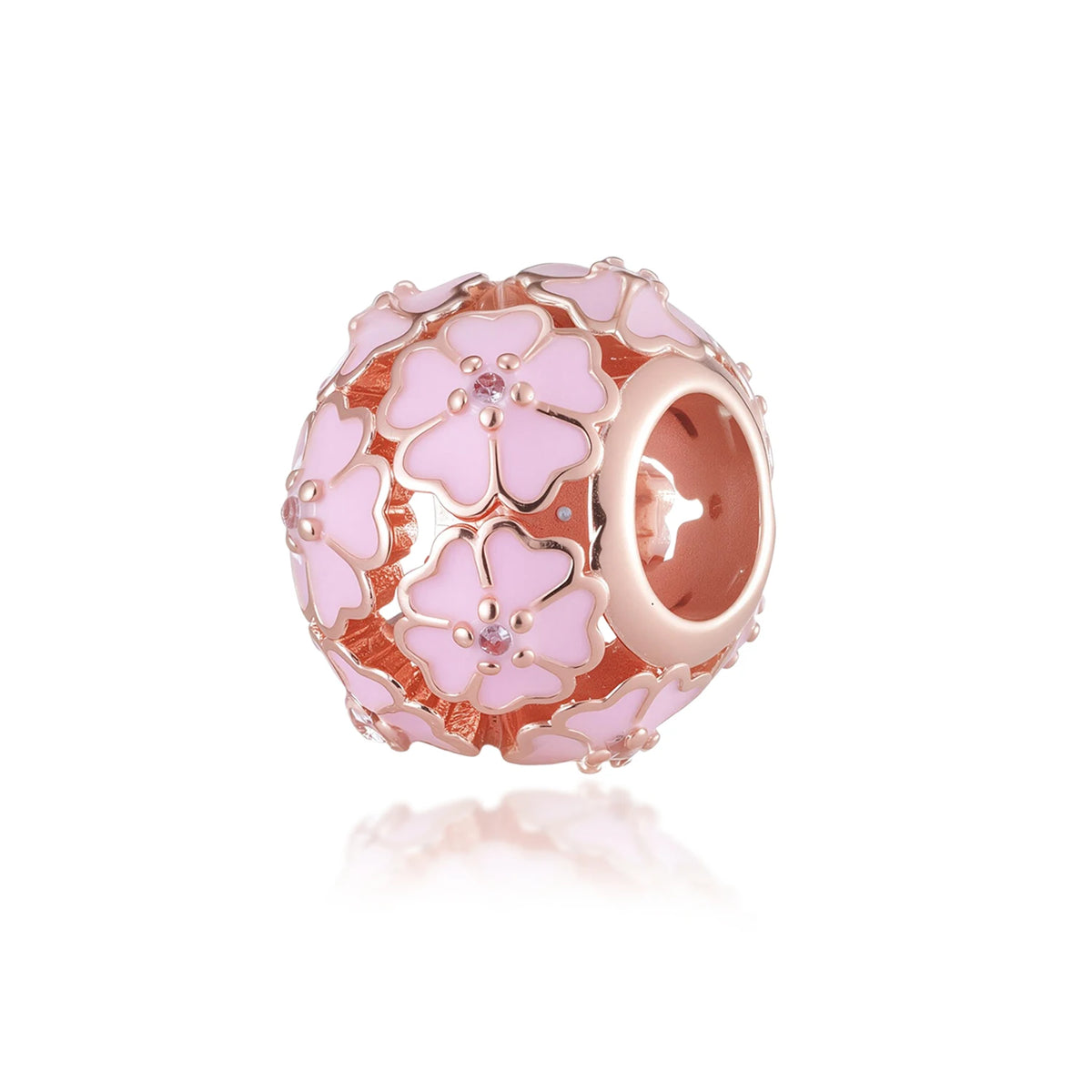 Un dije de color rosa y dorado con diseño floral y pequeñas piedras transparentes.