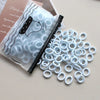 A pile of white elastic hair bands is shown next to a package featuring a cute animal design.