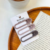 A set of vintage frosted geometry hair clips displayed on a white card against a wooden tray.
