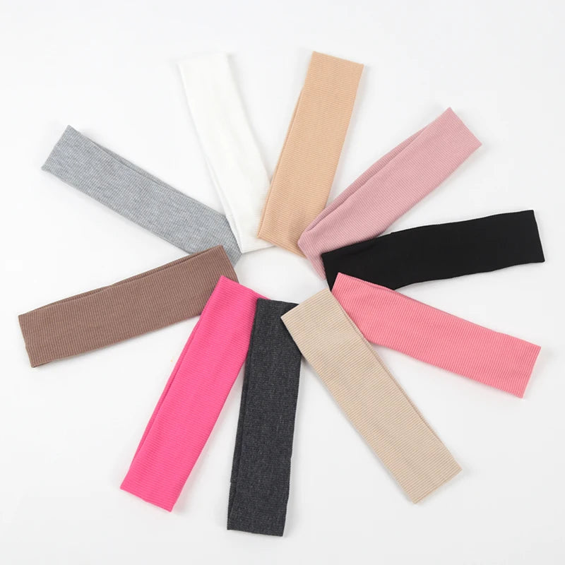 A collection of ten knitted elastic headbands in various shades including pink, beige, gray, and black.