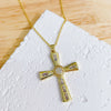 A dainty gold cross charm necklace with clear stones displayed on a white surface.