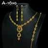 A set of luxury gold plated bridal jewelry featuring earrings and a necklace displayed on a black display stand.