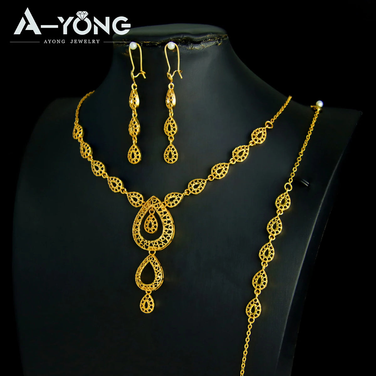 A set of luxury gold plated bridal jewelry featuring earrings and a necklace displayed on a black display stand.