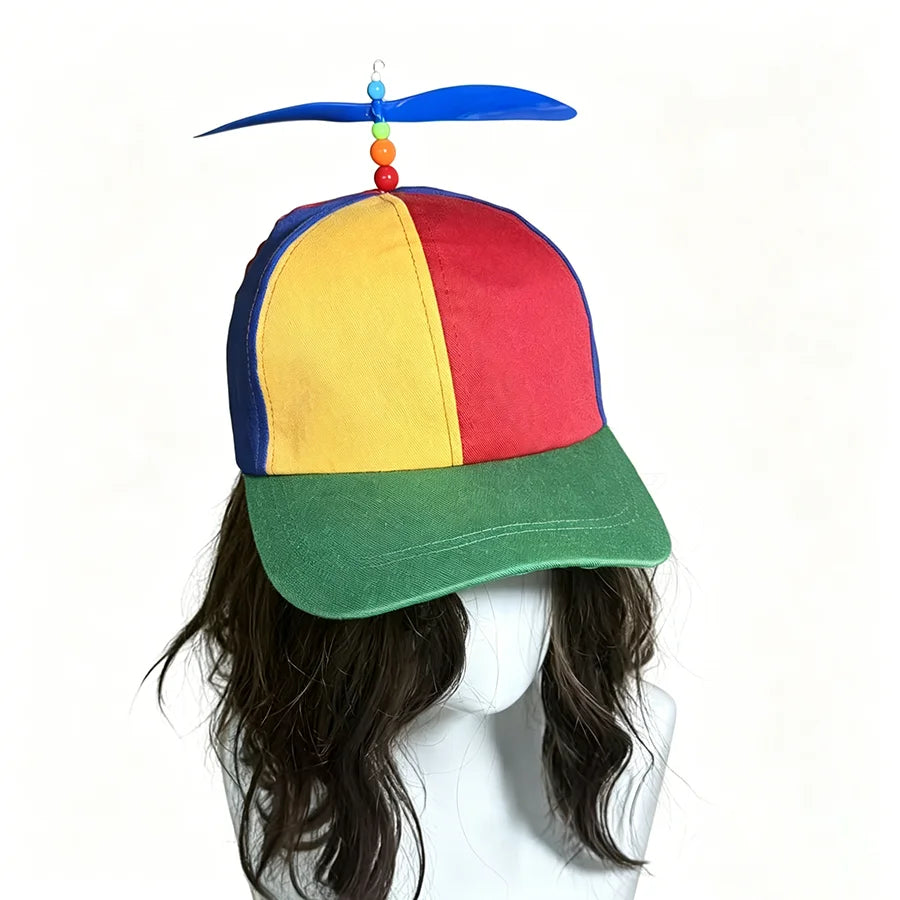 A colorful propeller hat with a rainbow-colored top and green brim is displayed on a person's head.