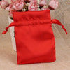 A bright red satin drawstring pouch filled with pink and white flowers.
