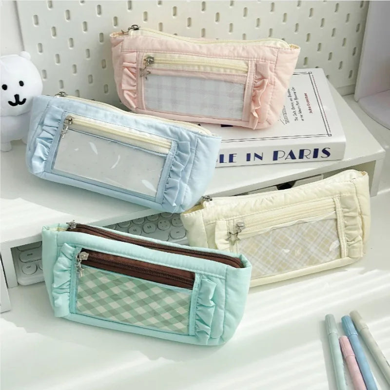 A collection of pastel-colored lace pencil cases in pink, blue, and cream are displayed on a white surface.
