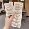 A hand holds a display of pearl brooch pins for customizing apparel, showing various sizes and styles.