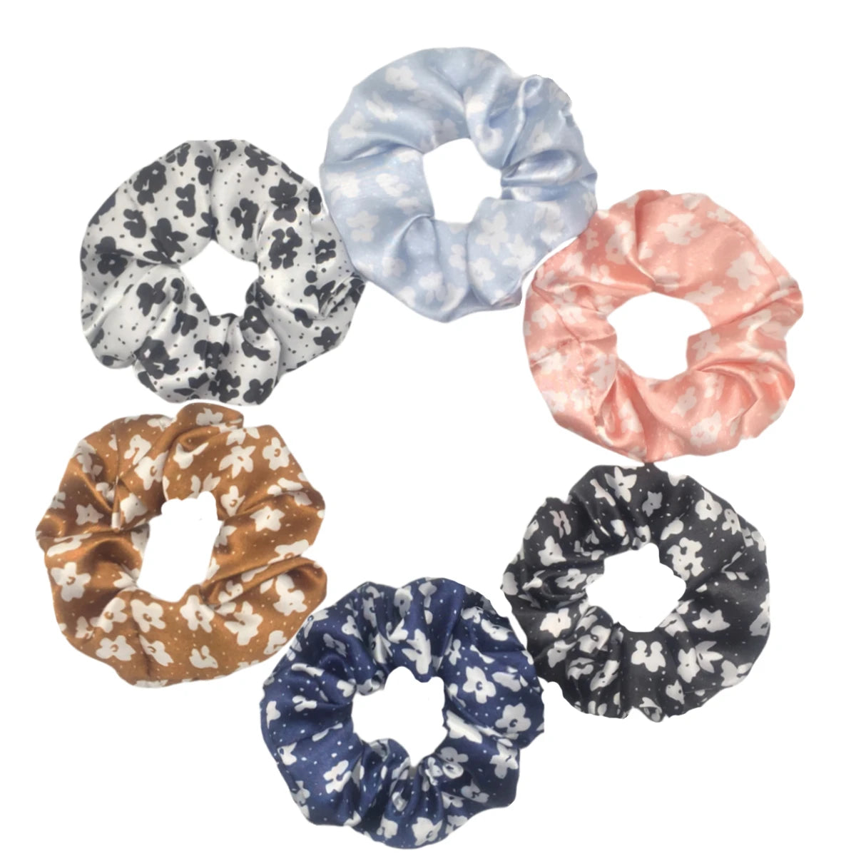 Un set de seis gomas para el pelo con estampado floral de satén en varios colores pastel y oscuros, dispuestos en círculo.