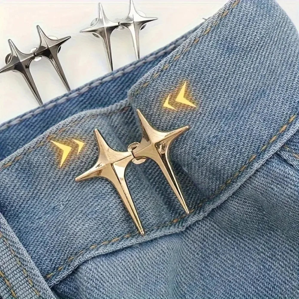 A pair of gold star-shaped decorative waist buckle buttons are shown against a blue denim fabric.
