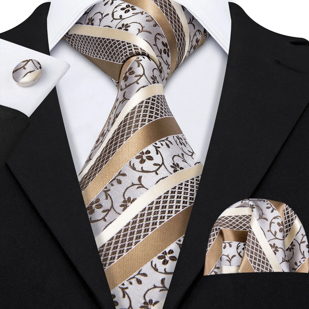 A close-up of a men's silk jacquard tie featuring silver and gold patterned fabric worn with a black suit jacket.