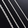 Primer plano de varias hebras de collares de cadena de cuerda plateada dispuestas en diagonal sobre una superficie oscura.