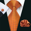 A close-up of an orange silk jacquard tie and matching shirt collar against a black background.