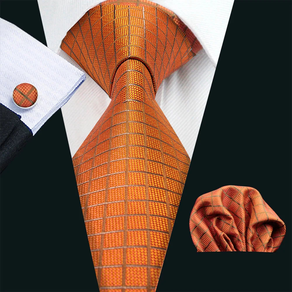 A close-up of an orange silk jacquard tie and matching shirt collar against a black background.
