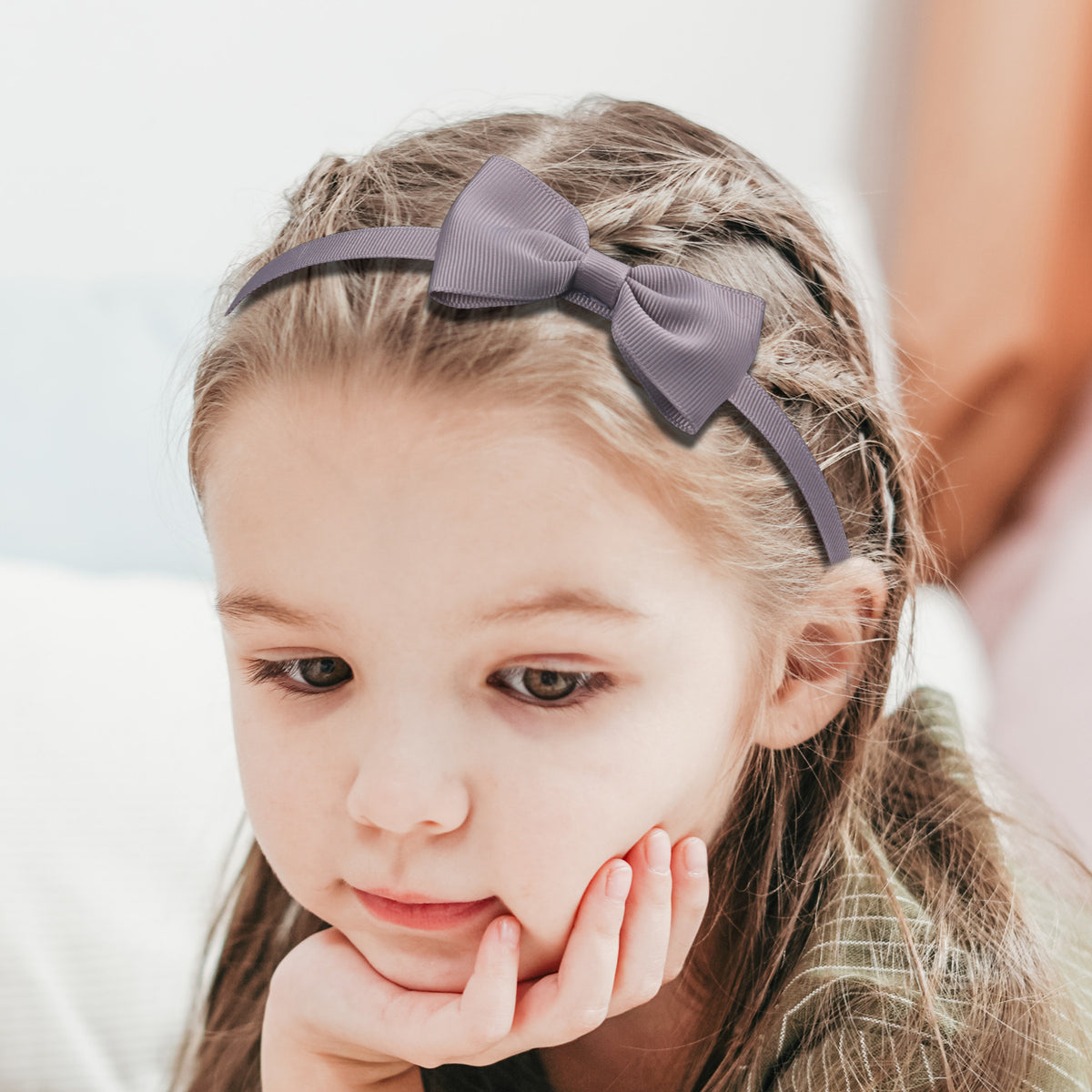 A young girl with light brown hair is shown wearing a gray grosgrain ribbon hair bow.
