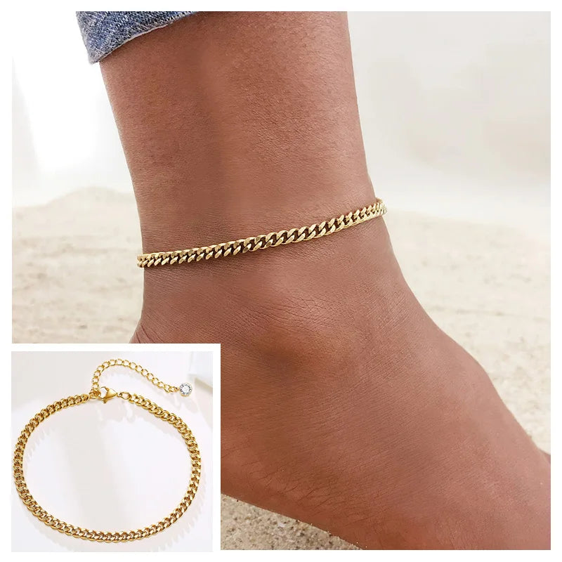 A close-up of a gold-toned snake chain anklet worn on a person's ankle.