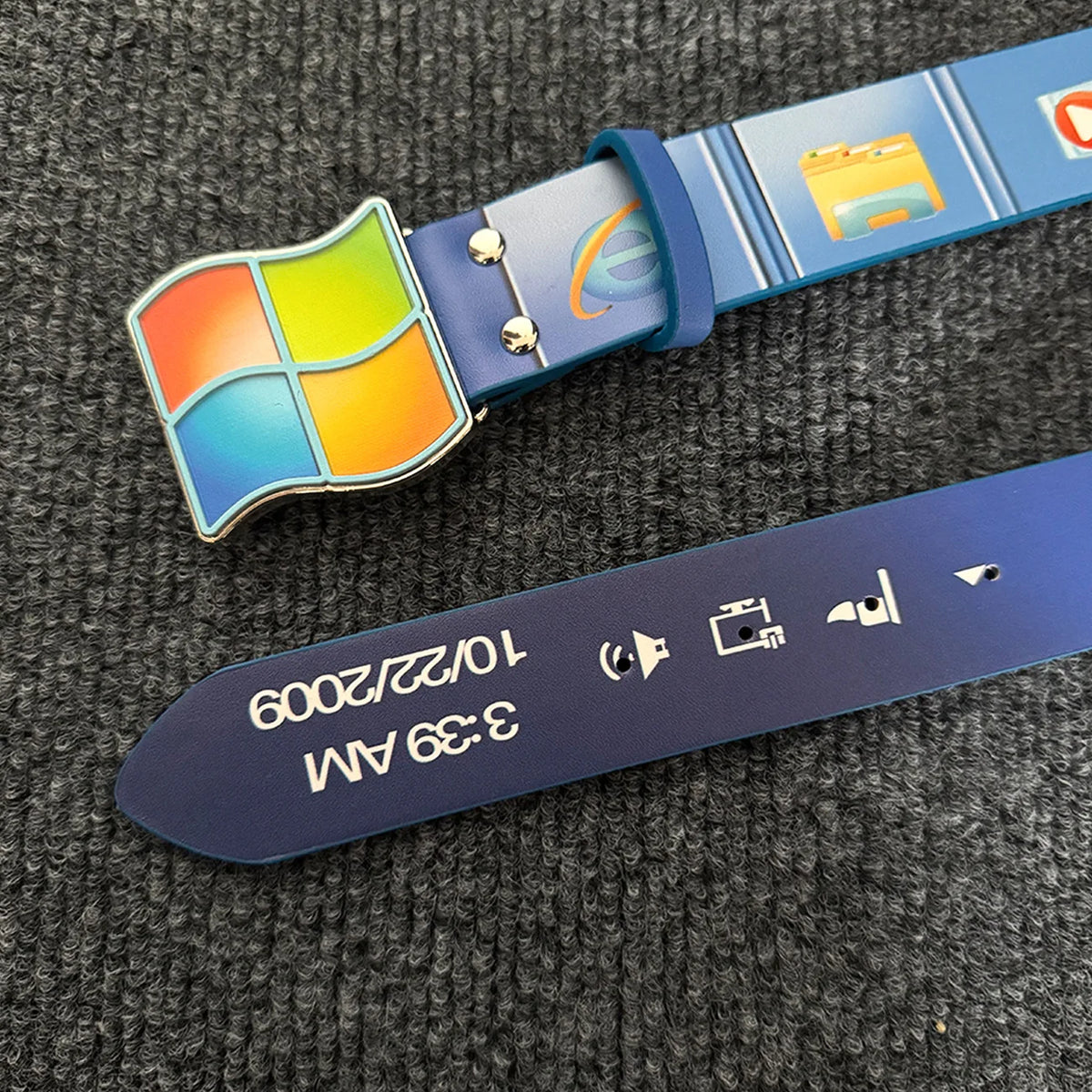 Cinturón de impresión de computadora azul con un logo colorido y una pantalla rectangular que muestra las 3:39 AM y una fecha
