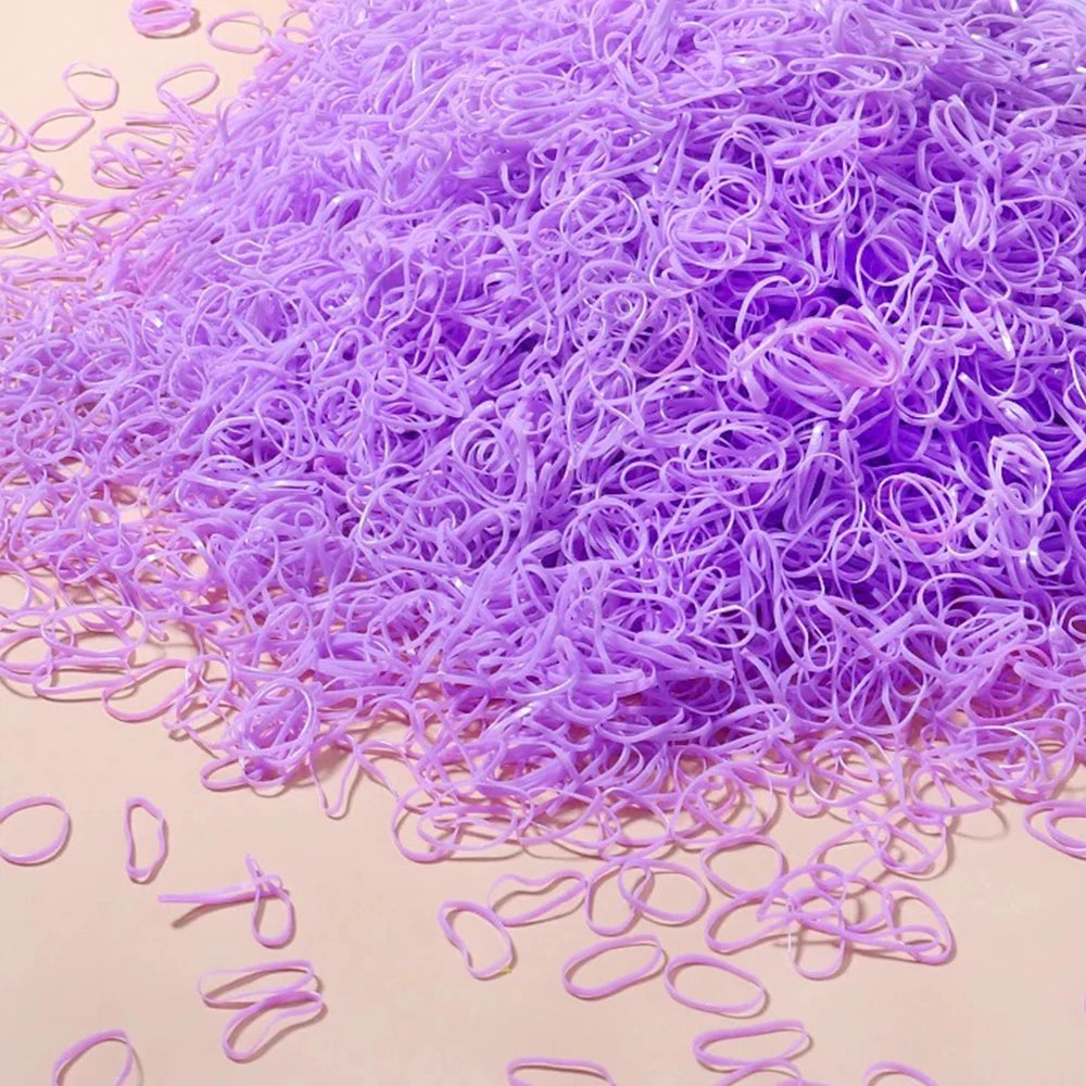 A pile of purple disposable rubber hair ties for kids scattered on a light surface.