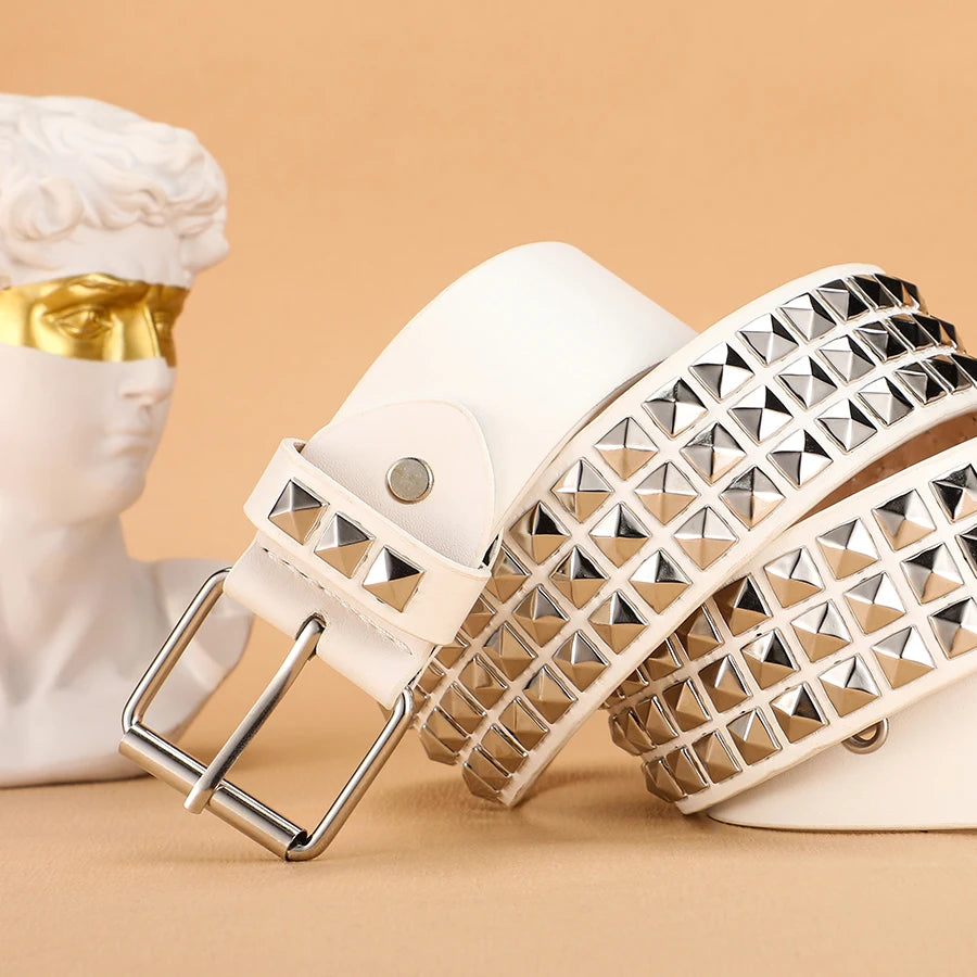 A close-up of a beige leather belt adorned with silver metal rivets and studs, displayed next to a white bust.