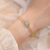 Nahaufnahme eines gold-silbernen, verstellbaren Armbandes mit Sonne- und Mond-Anhängern am Handgelenk.