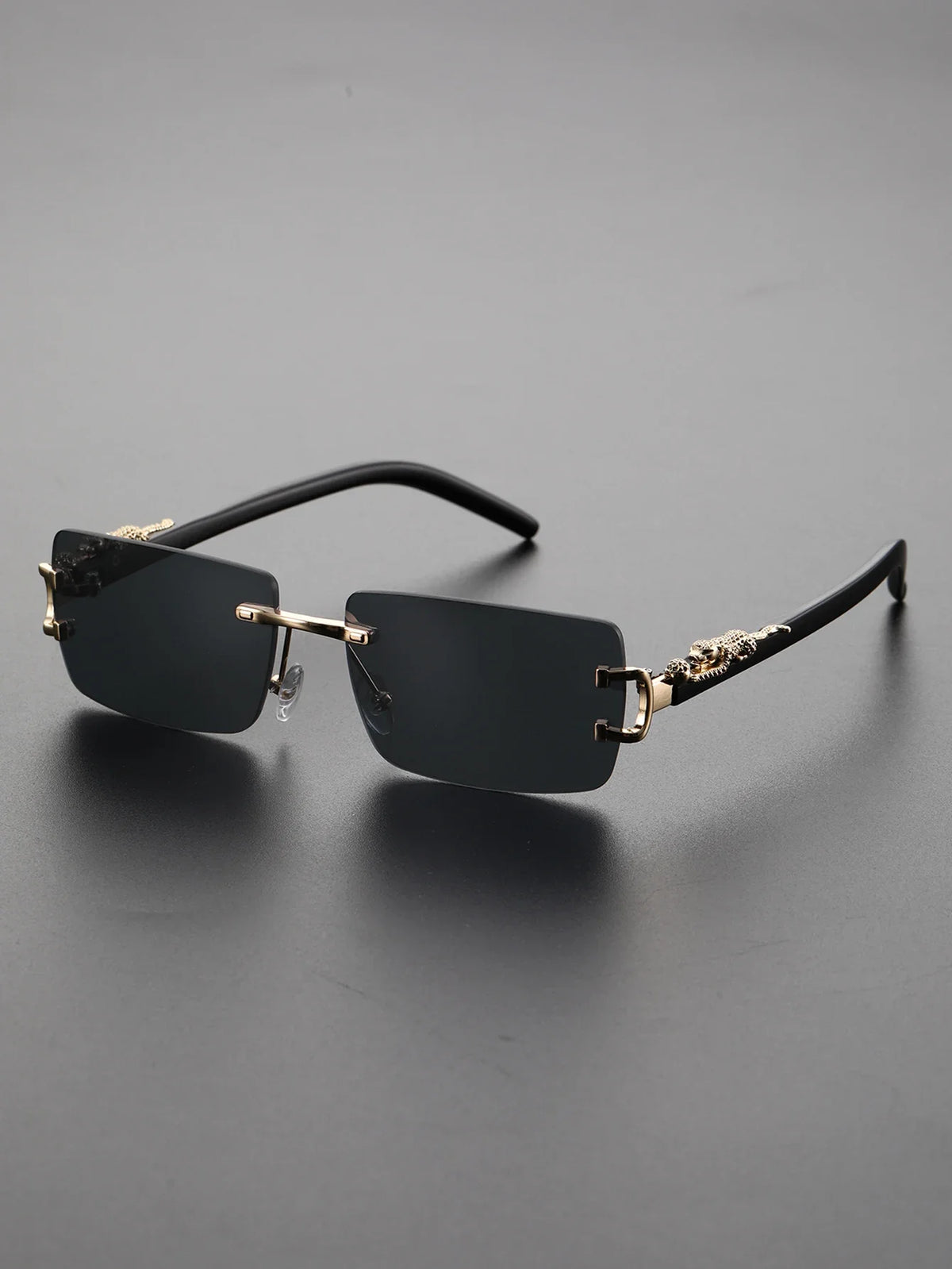 Black rectangular sunglasses with gold accents resting on a dark surface.