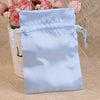 Light blue satin drawstring jewelry pouch with pink flowers in the background
