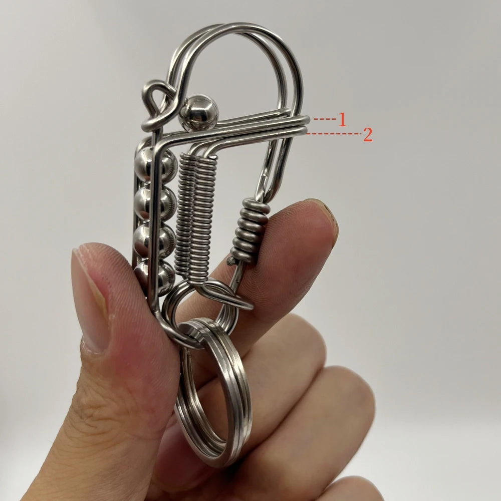 Une main tient un porte-clés mécanique en acier inoxydable avec un ressort et un anneau circulaire.