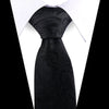 Black silk necktie with an elegant floral paisley pattern worn under a white shirt.