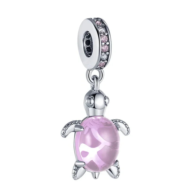 Cuenta de plata con una perla esférica rosada y translúcida y una pequeña figura de animal.