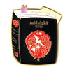Broche émail couleur or avec fond noir, motif de poisson rouge et les mots 'midnight sun'.