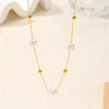Un délicat collier en or avec de petits charms de perles blanches rondes.