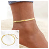 Gold stainless steel snake chain anklet worn on a woman's ankle.