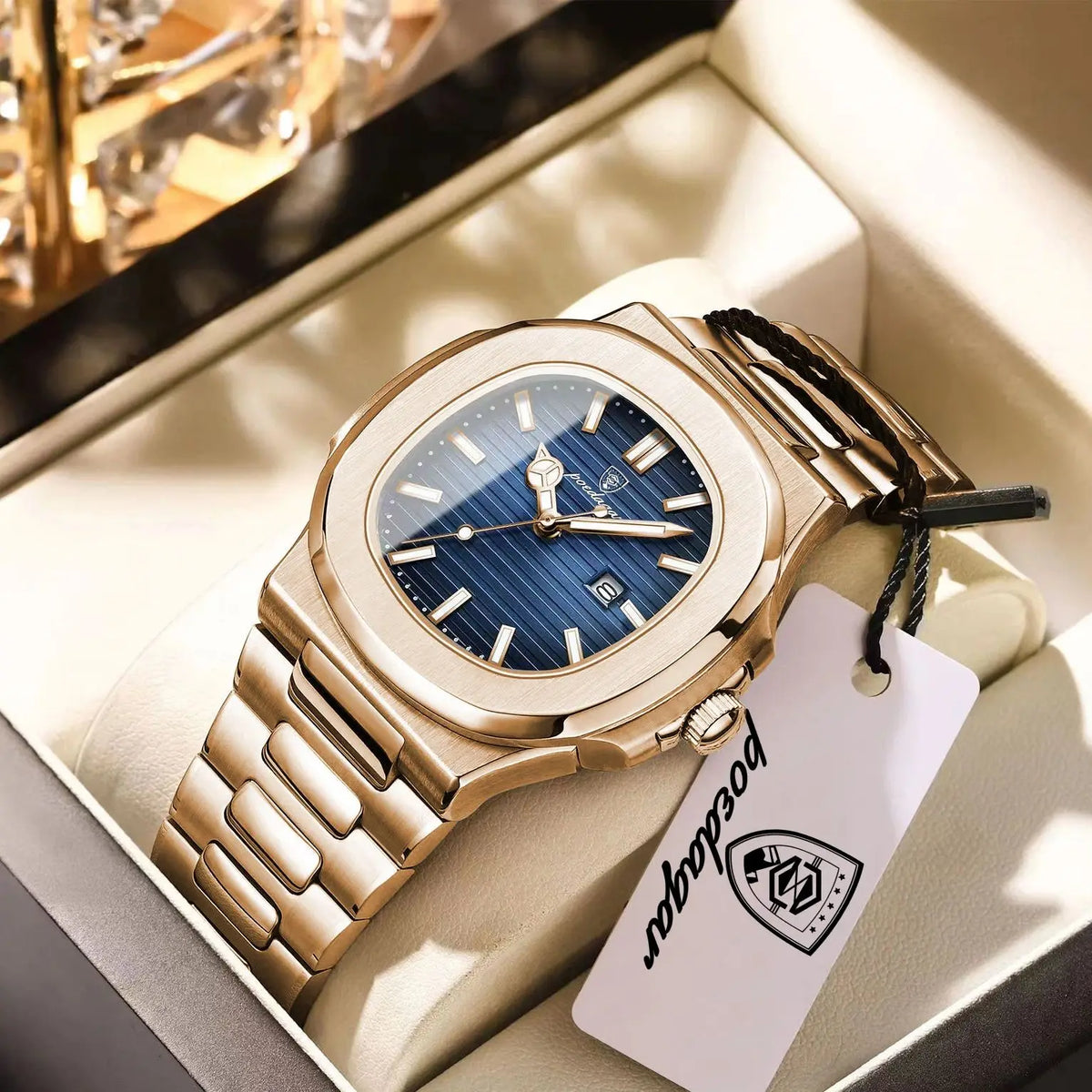 Nahaufnahme einer goldfarbenen Edelstahluhr mit blauem Zifferblatt und schwarzem Armband in einer hellen Box.