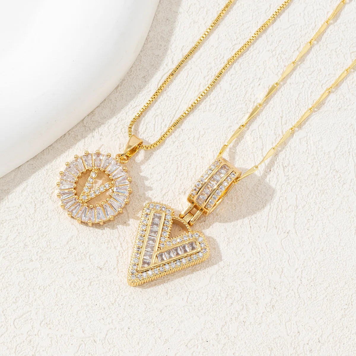 Gold-toned necklace set featuring crystal pendants shaped like the letters A and V.